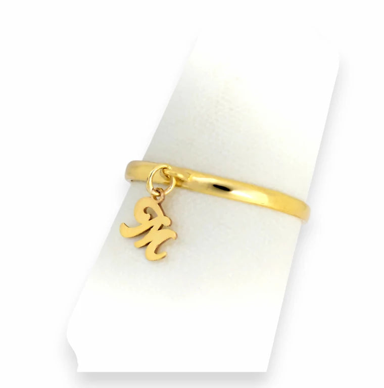 Close-up of custom M letter charm ring in real gold, dangling script initial on smooth minimalist band.